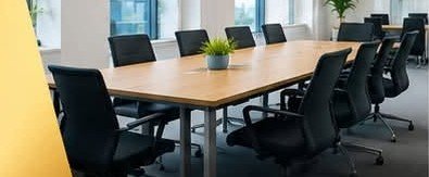 A clean, tidy boardroom with a wooden table and office chairs
